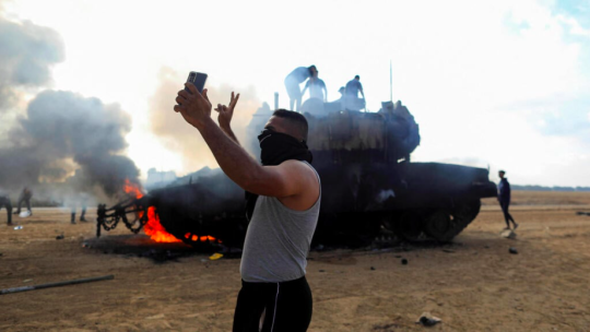 Teroriști Hamas, pe un tanc israelian în flăcări. Foto: ynetnews.com